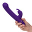 A hand model holds a purple silicone clitoral suction rabbit vibrator for scale.