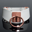 A white faux leather contoured  collar with a big rose gold O-ring in the centre. 