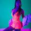 An editorial shot of a model wearing a pink chemise under black light to showcase its glow-in-the design. 