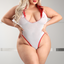 A curvy model wears a sheer white mesh nurse teddy with a plunging v-neckline.