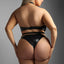 Back view of a curvy model wearing a black croc print wet look bra with high-cut panties.