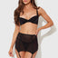 A model wears a black satin bra and garter skirt with thong combining sheer mesh with smooth satin microfibre panels. 