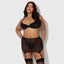 A plus size model wears a sheer black satin bra, panty and garter skirt with satin elastic panty sides.