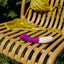 An app compatible silicone purple and white g-spot vibrator sits on a chair next to a bikini. 