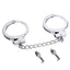 A pair of metal handcuffs lays on a white backdrop with 2 x skull-shaped keys next to it.