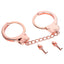 A pair of rose gold handcuffs lays on a white backdrop with 2 x skull-shaped keys next to it.