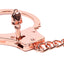 Close up of a skull-shaped key slotting into its keyhole of a rose gold metal handcuff. 