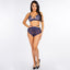 A model wears a navy blue lace bralette with satin-sheen elastic cage strap details. 