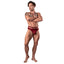 A male model wears a red lace strappy cut-out thong with a contoured front pouch. 