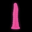 A pink ribbed dildo with a wide suction cup base stands in on a black backdrop showcasing its glow in the dark properties.