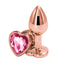 A pair of rose gold metal plugs stands against a white backdrop showcasing its pink gem heart-shape flared stopper base. 