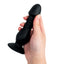 A hand model holds a black thrusting vibrating butt plug showcasing its scale. 