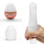A hand model holds a Tenga firm egg masturbator showcasing it stretched over a dildo. 