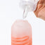 Close up of a hand model squeezing Tenga's water based lubricant on top of the tip of a dildo. 