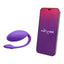 A We-Vibe wearable egg vibrator in purple sits next to a cellphone showcasing its app compatibility. 