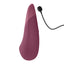 A dusty pink noiseless clitoral vibrator stands next to its magnetic charging cord. 