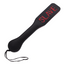 A faux leather slave imprint spanking paddle with a hanging loop lays flat against a white backdrop.