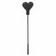 A black faux leather heart shaped riding crop lays flat against a white backdrop. 