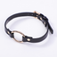 A black faux leather gold o-ring choker with an adjustable rear closure lays flat against a white backdrop. 