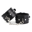 A pair of  black leather wrist cuffs with a faux black fur interior sits against a white backdrop.