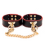 A pair of black and red faux leather push stud wrist cuffs with large O-rings.