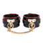 A pair of black and red faux leather wrist cuffs with gold adjustable buckle closures. 